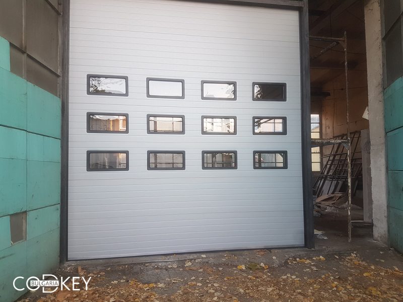 Индустриална секционна врата в град Русе с три реда остъклени с декоративни прозорци панели_001